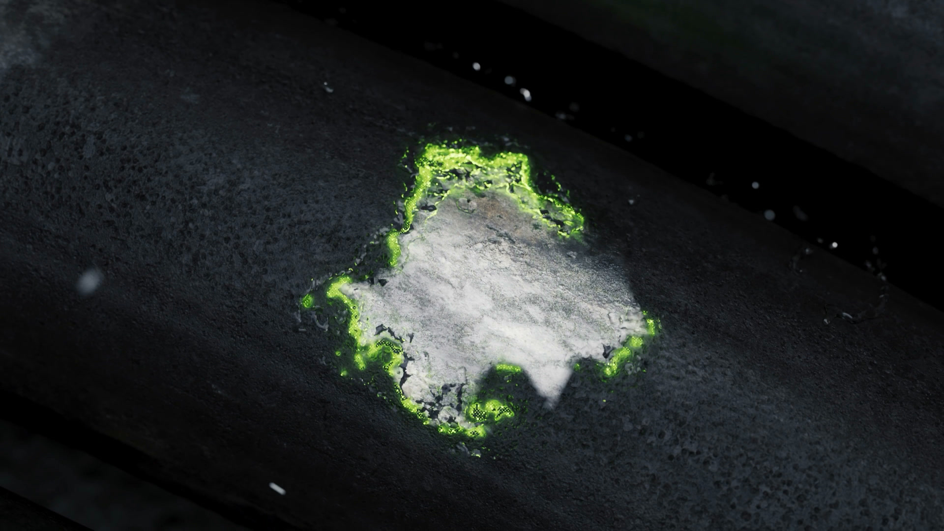 Pipe surface with a dark deposit; a bright exposed patch with a glowing green edge at its centre.