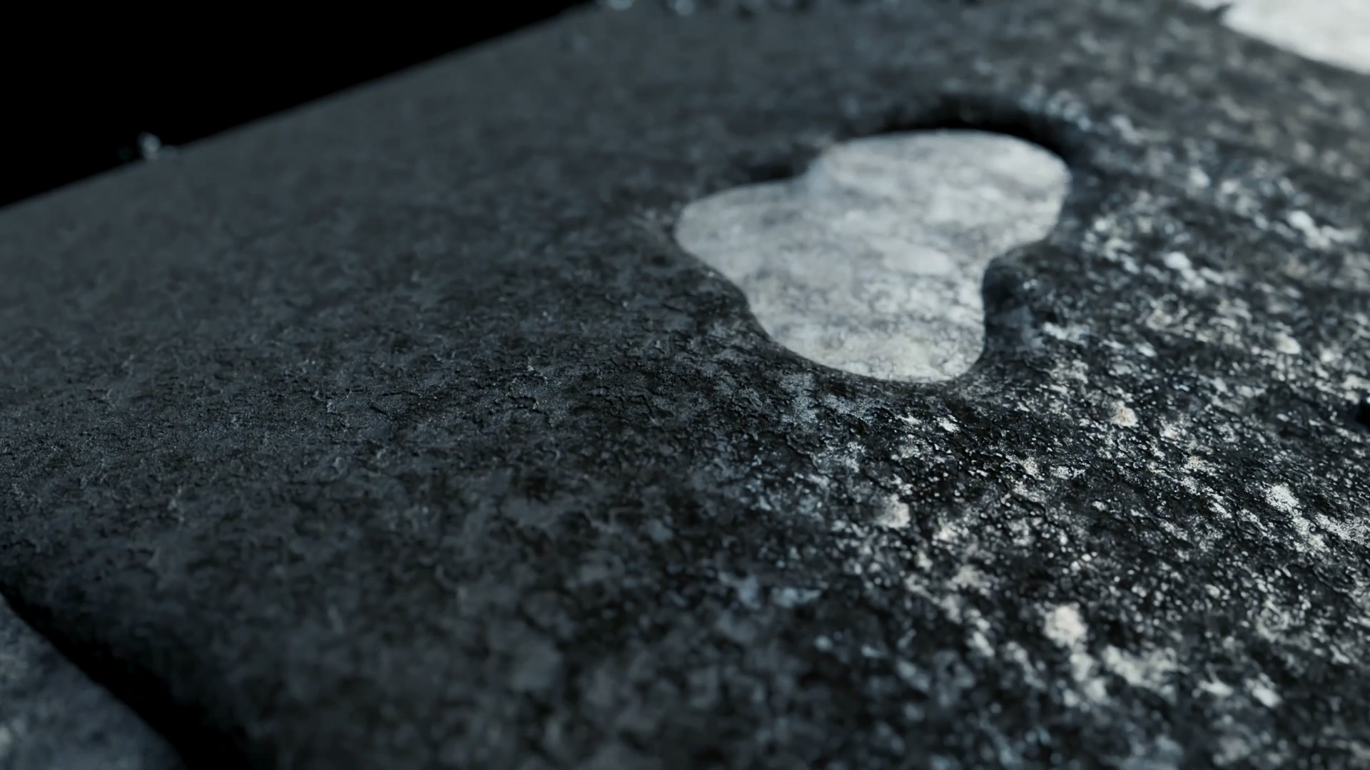 Angled view of the pipe surface with a bright, exposed patch of metal in the dark deposit.