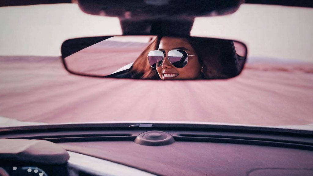 Fahrerin mit Sonnenbrille im Rückspiegel auf Wüstenstraße – KI-generiert mit Veo 3.1