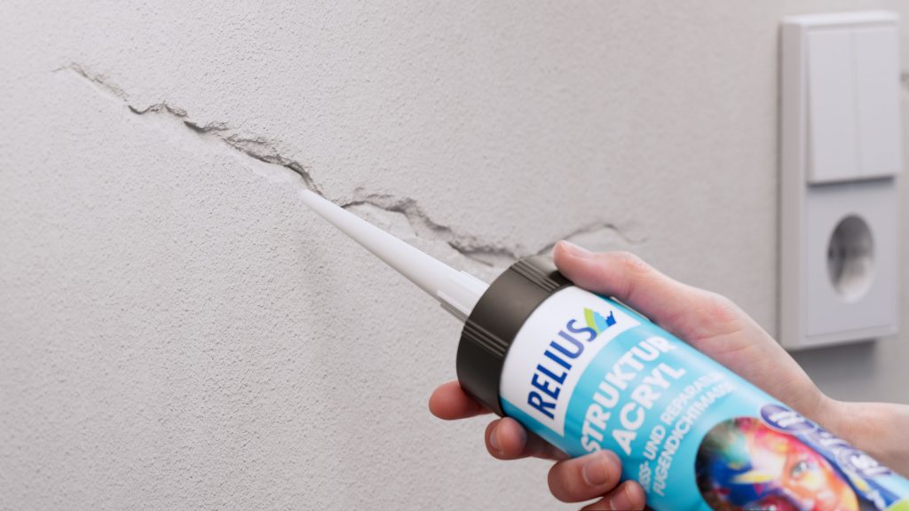 Auftrag des Relius Struktur Acryls zur Reparatur eines Risses in einer Putzwand, Anwendungsmotiv aus hybrider Bildproduktion